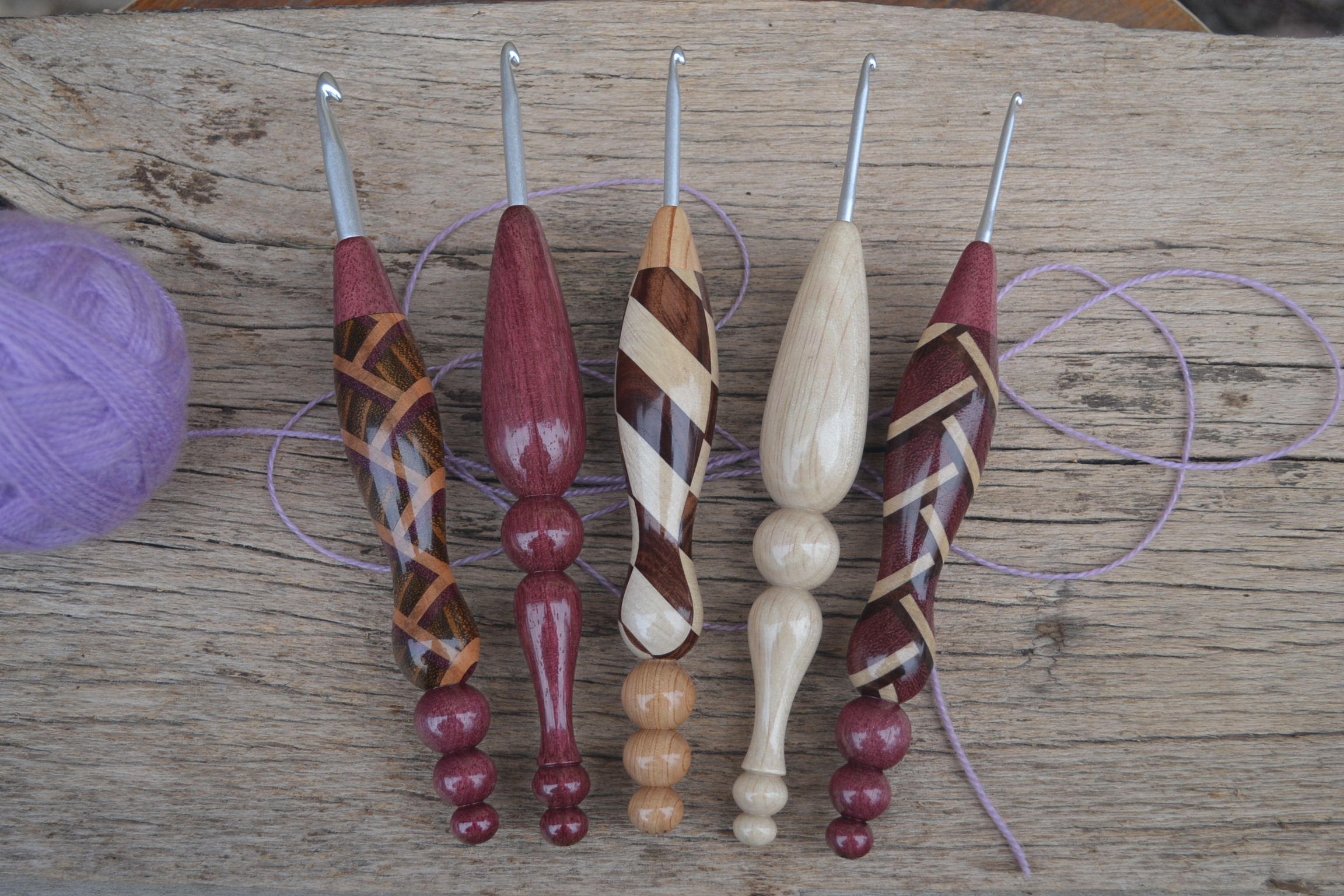 Set of five handcrafted ergonomic crochet hooks with Clover Amour metal tips, featuring lacquered handles made from solid wood and mosaic designs.