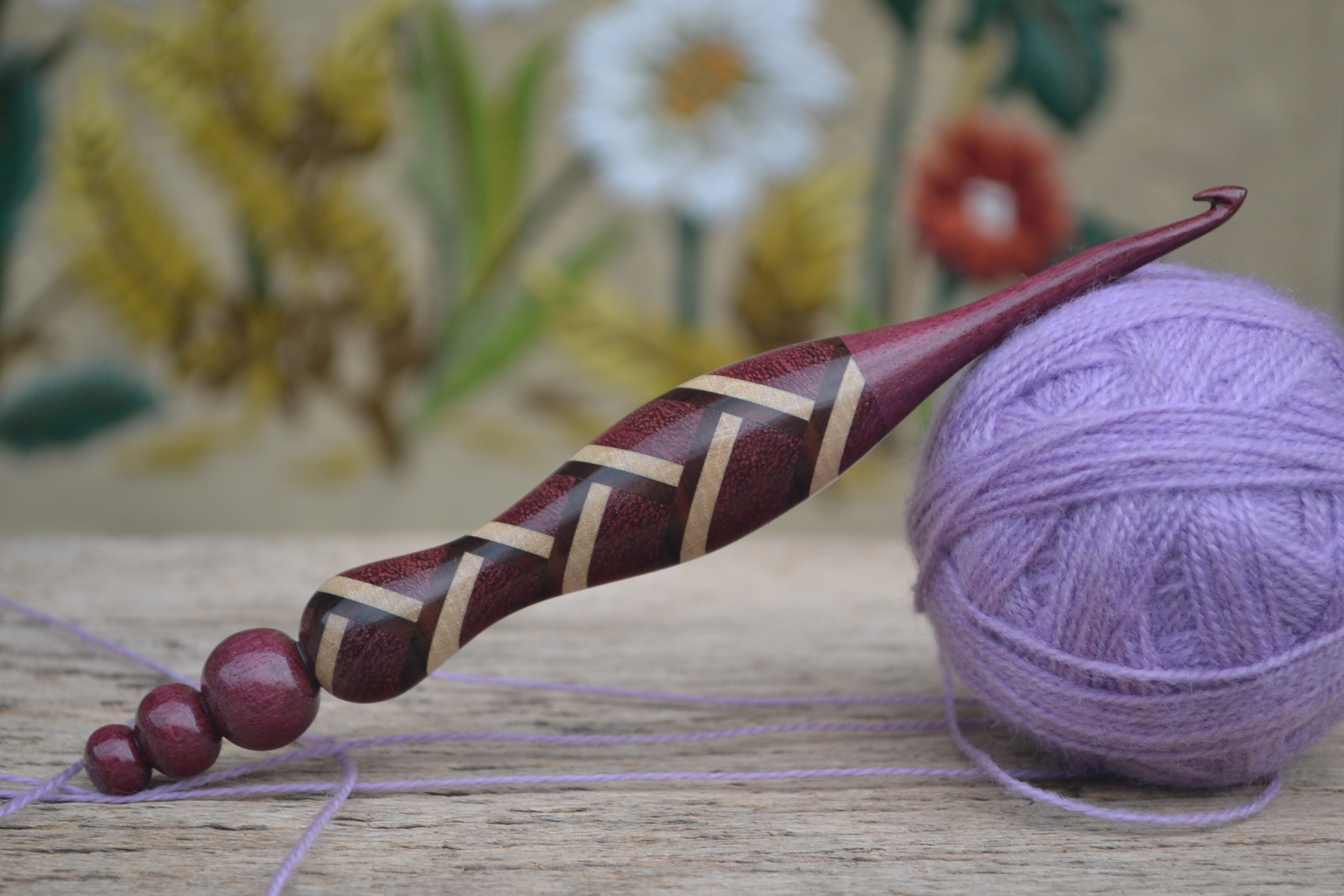 Handmade ergonomic crochet hook, 5.5mm (Size I), crafted from amaranth, hornbeam, and dark apricot wood, reinforced with a metal rod.